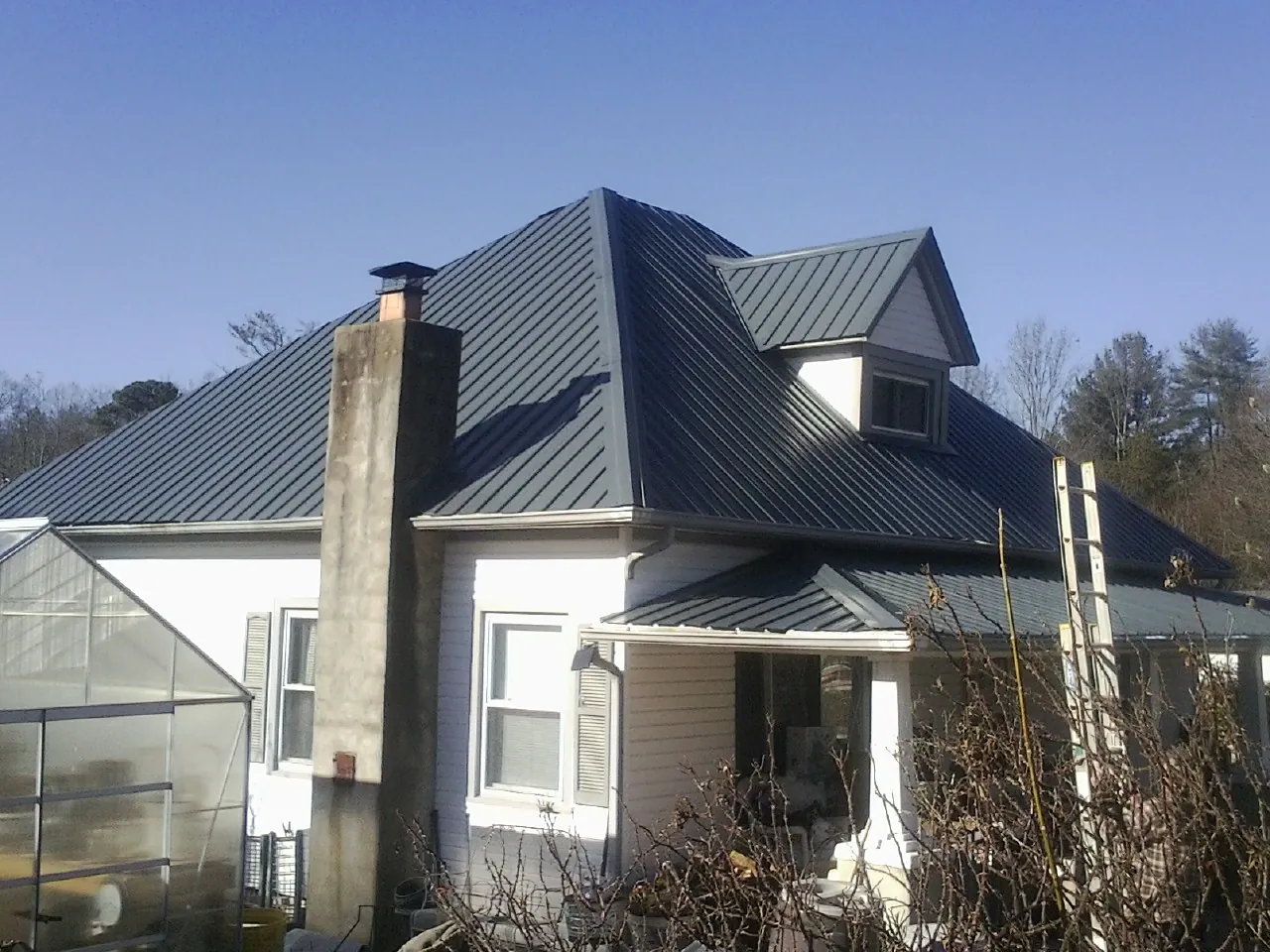 Dark blue standing seam metal roof on a white farmhouse with dormer — Slate & Tile Roof Repair by Roofing Brothers in Williamstown