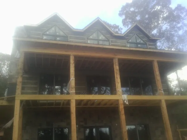 Dormers and porch framing on a large log home under construction — Roof Coating work by our crew in Williamstown