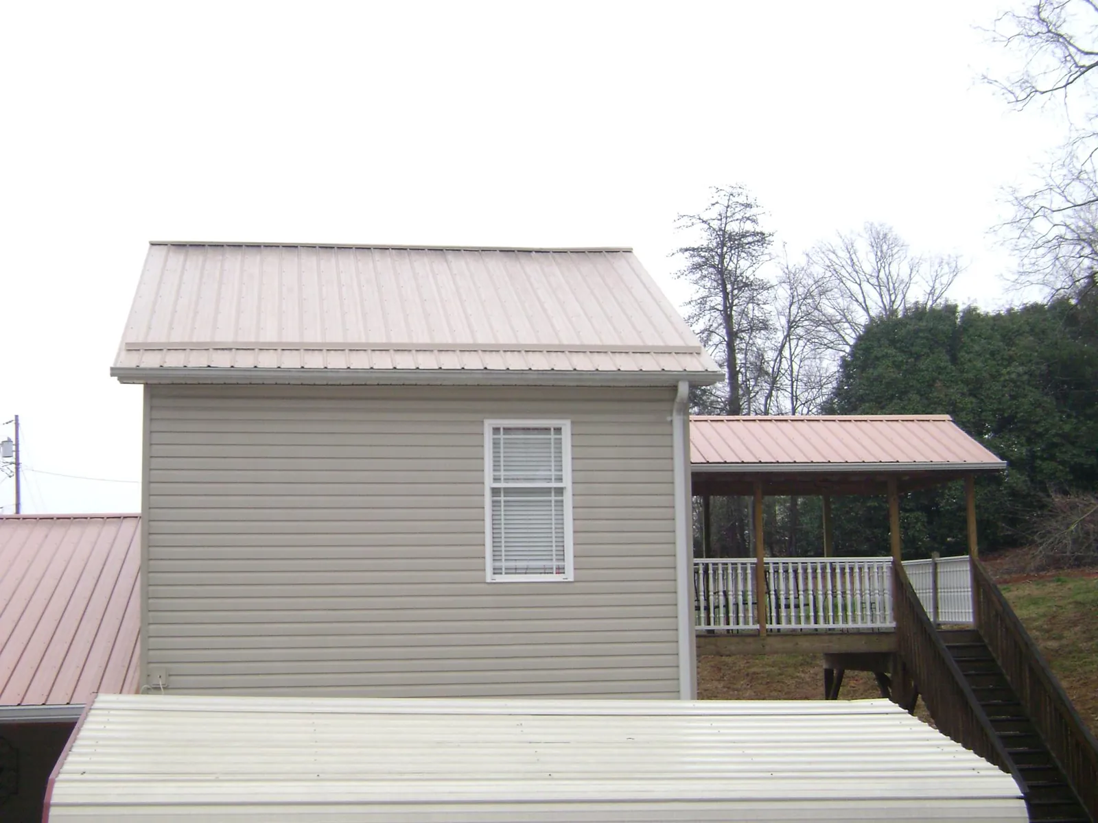 Tan metal roofs on a two story addition and attached porch, from a Roof Replacement job in Williamstown